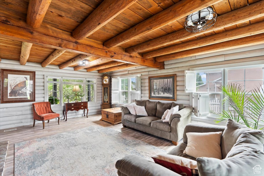 Living room featuring wood ceiling with exposed beams, log walls, and wood finished floors