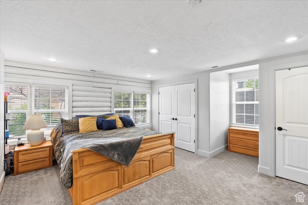 Bedroom with light carpet, a textured ceiling, recessed lighting, and baseboards