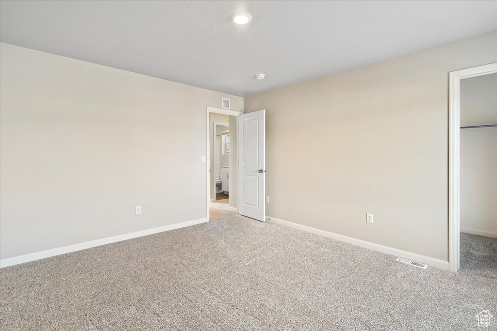 Unfurnished bedroom featuring carpet, baseboards, a closet, a walk in closet, and recessed lighting