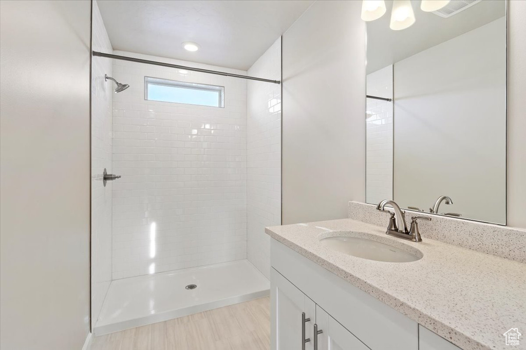 Bathroom featuring tiled shower and vanity