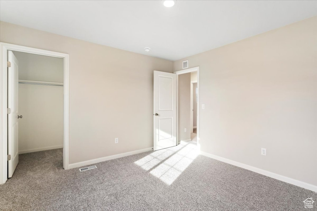 Unfurnished bedroom featuring carpet flooring, baseboards, a closet, and a walk in closet