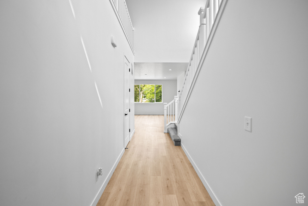 Hallway featuring light wood-style flooring, stairway, and baseboards