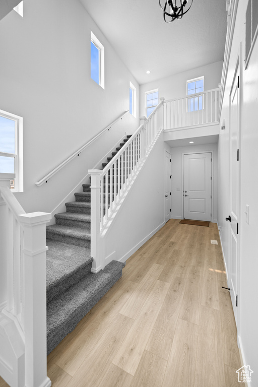 Foyer with stairs, wood finished floors, a towering ceiling, recessed lighting, and baseboards