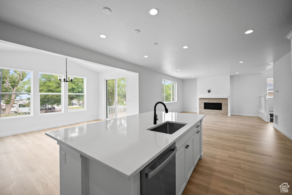 Kitchen with a sink, stainless steel dishwasher, open floor plan, recessed lighting, and a fireplace