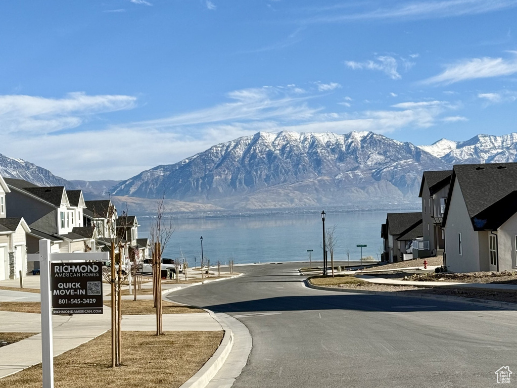 View of asphalt road with a water and mountain view and curbs