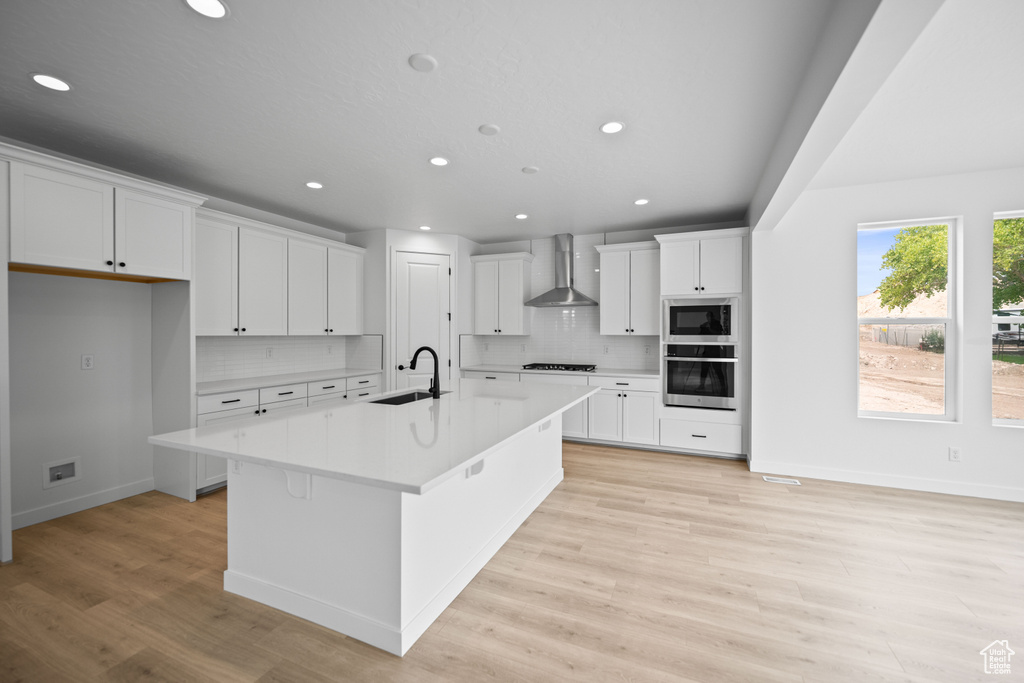Kitchen featuring wall chimney exhaust hood, a sink, stainless steel oven, built in microwave, and recessed lighting