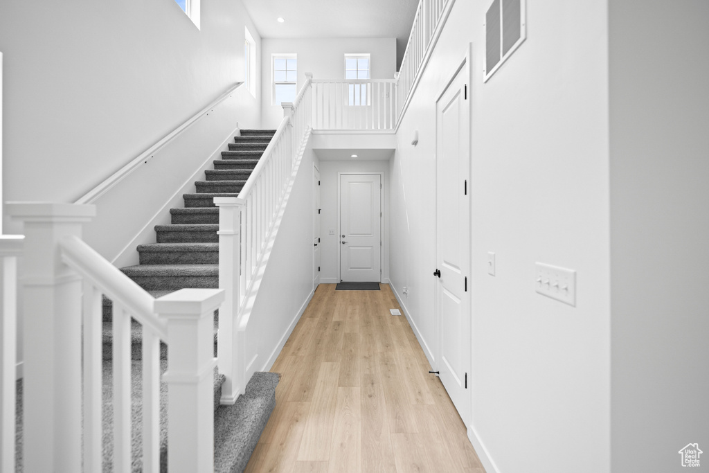 Entrance foyer featuring a towering ceiling, light wood finished floors, and stairs