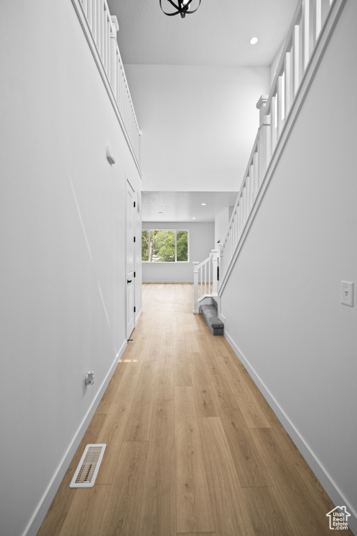Hallway with stairs, baseboards, light wood-type flooring, and recessed lighting