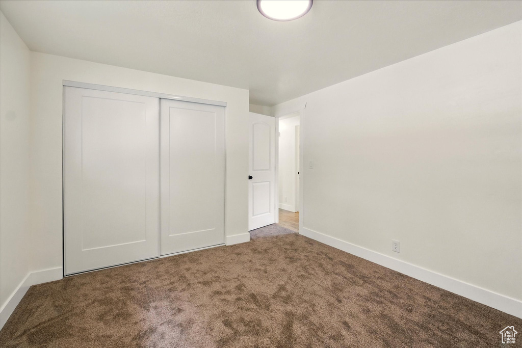 Unfurnished bedroom featuring carpet flooring, a closet, and baseboards