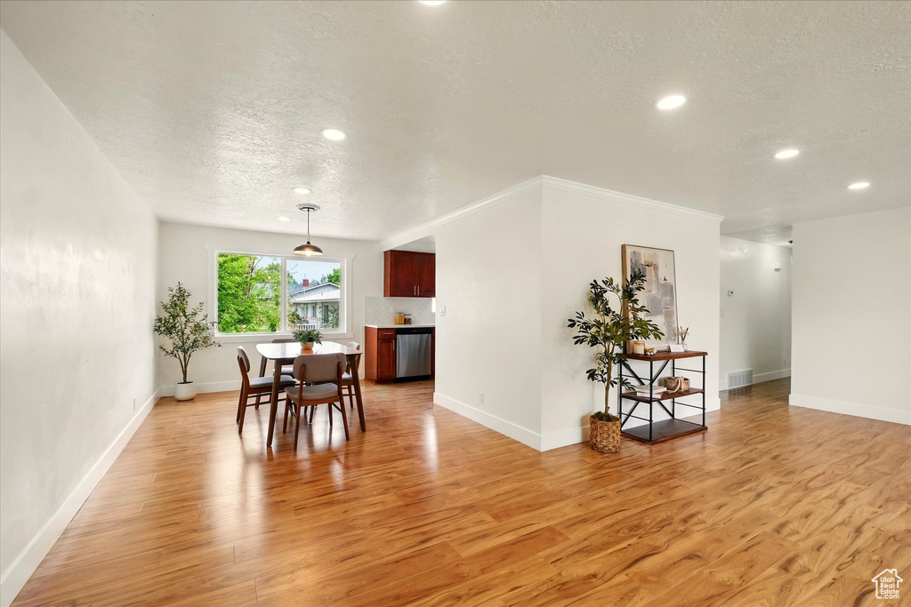Dining room featuring a textured ceiling, light wood-style flooring, recessed lighting, and baseboards