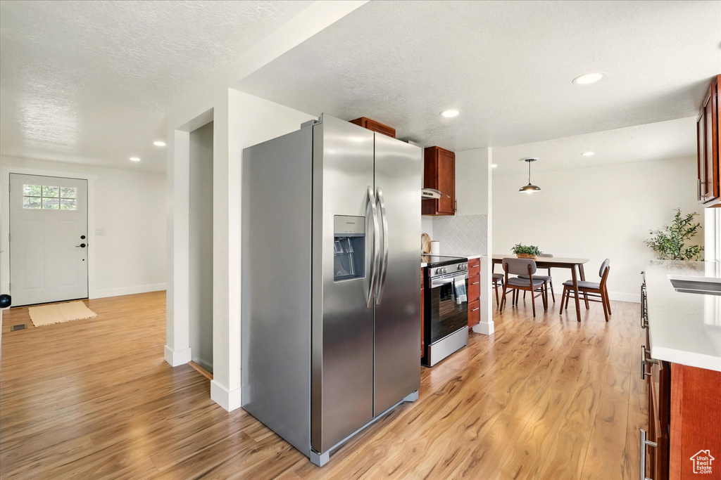 Kitchen featuring appliances with stainless steel finishes, light wood-type flooring, baseboards, decorative backsplash, and recessed lighting