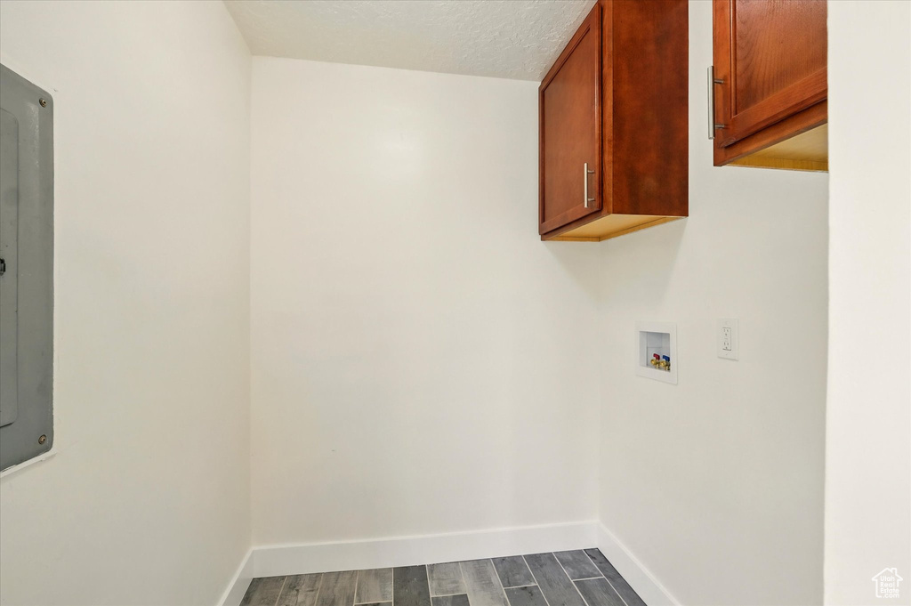Washroom featuring cabinet space, hookup for a washing machine, dark wood-type flooring, and baseboards