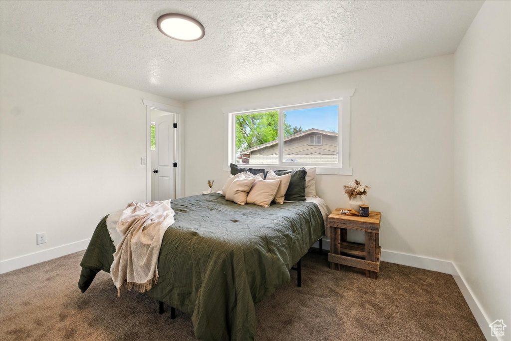Carpeted bedroom featuring baseboards and a textured ceiling