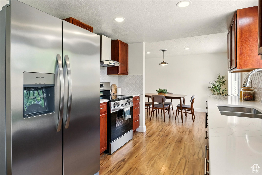 Kitchen with stainless steel appliances, a sink, light wood-type flooring, recessed lighting, and tasteful backsplash