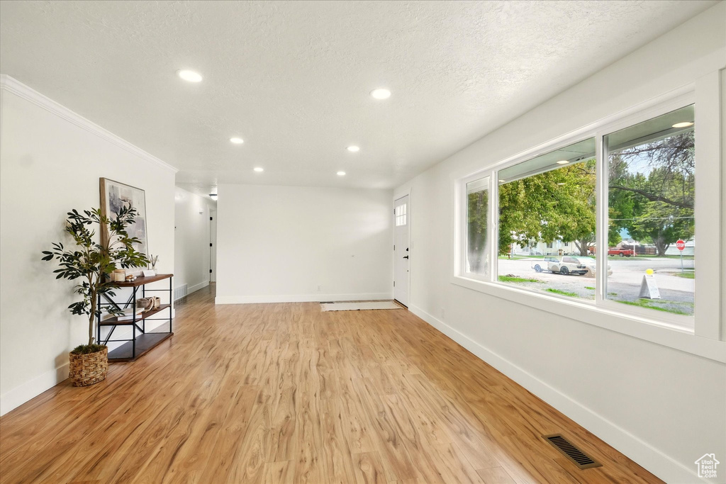 Empty room featuring recessed lighting, baseboards, light wood-style floors, and a textured ceiling
