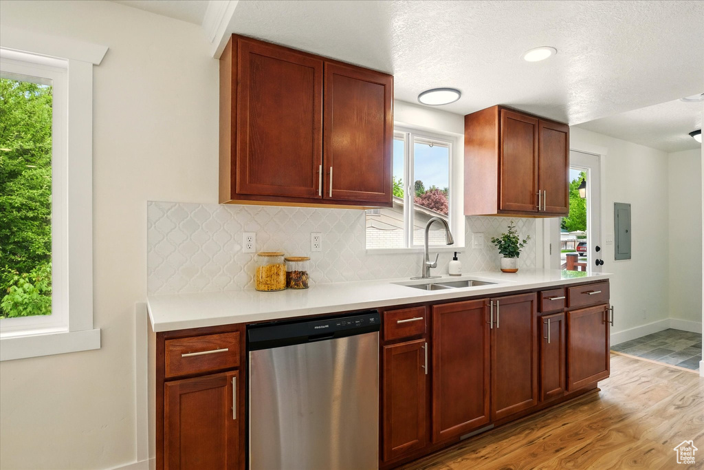 Kitchen with stainless steel dishwasher, a sink, decorative backsplash, light wood finished floors, and plenty of natural light