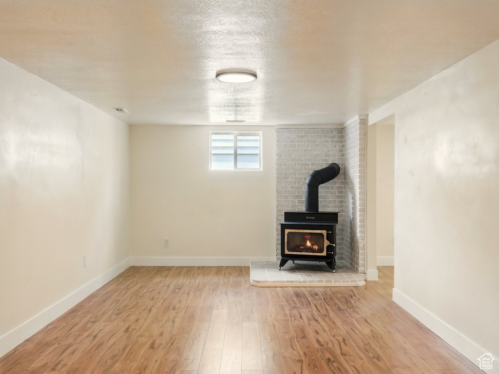 Unfurnished living room with wood finished floors, a wood stove, and baseboards