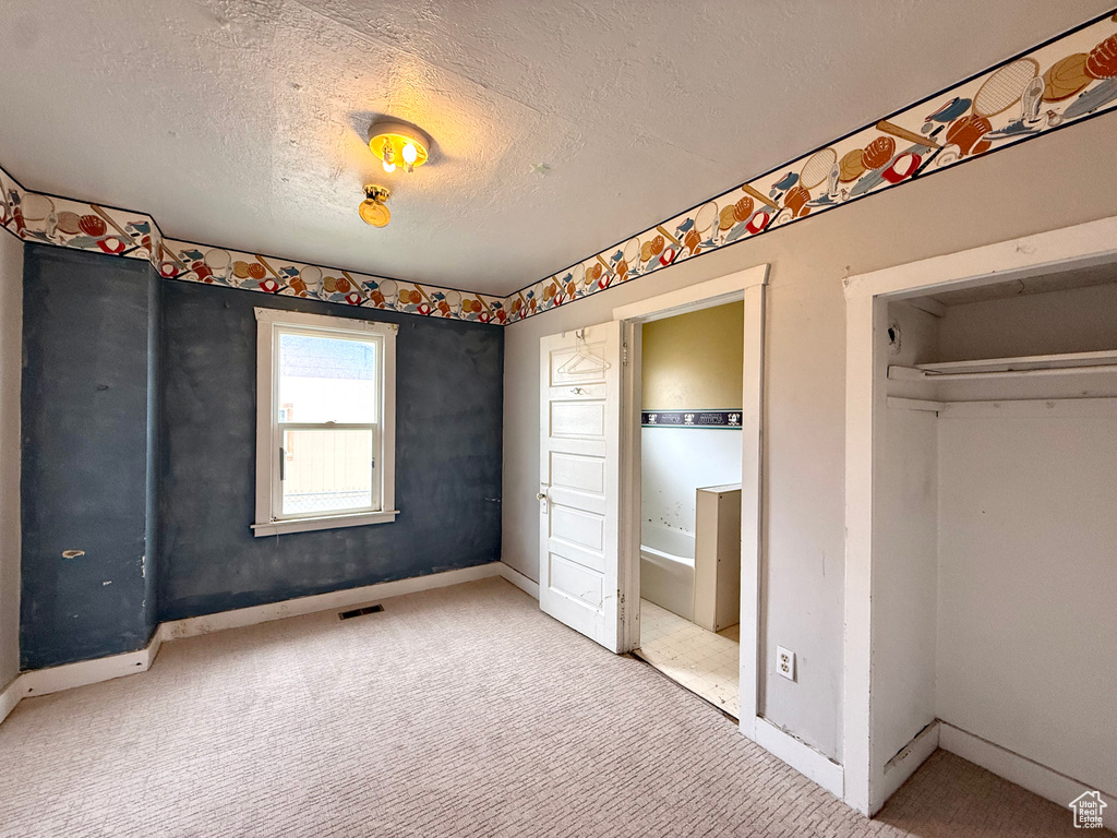 Unfurnished bedroom featuring carpet floors, baseboards, and a textured ceiling