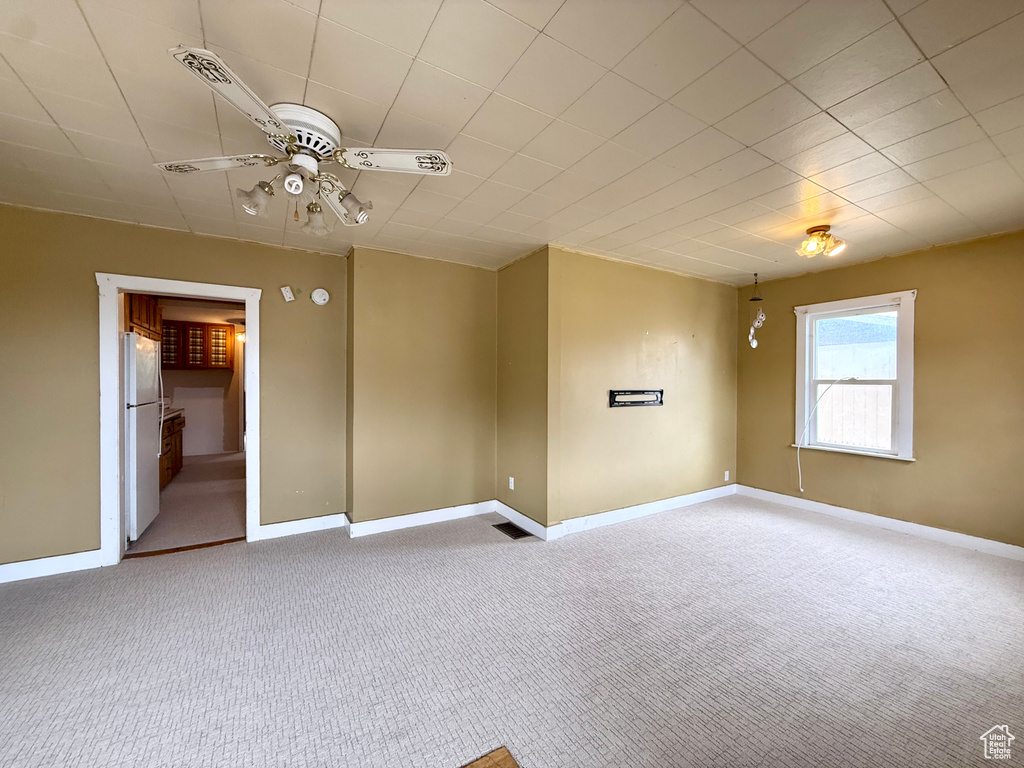 Carpeted empty room with a ceiling fan and baseboards