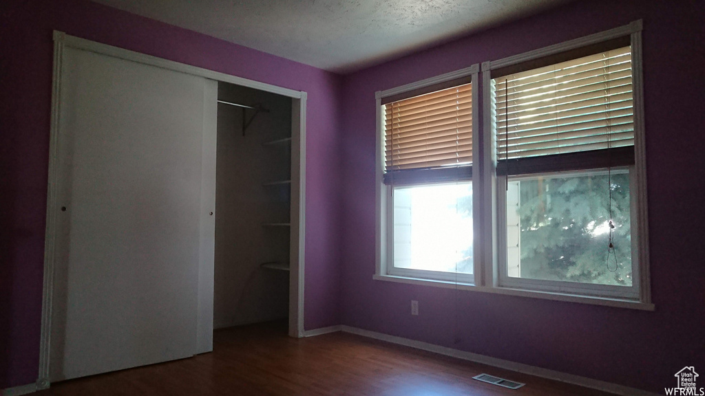 Unfurnished bedroom with wood finished floors, a closet, and baseboards