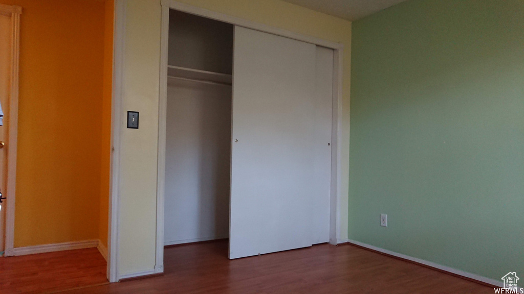 Unfurnished bedroom with a closet, wood finished floors, and baseboards