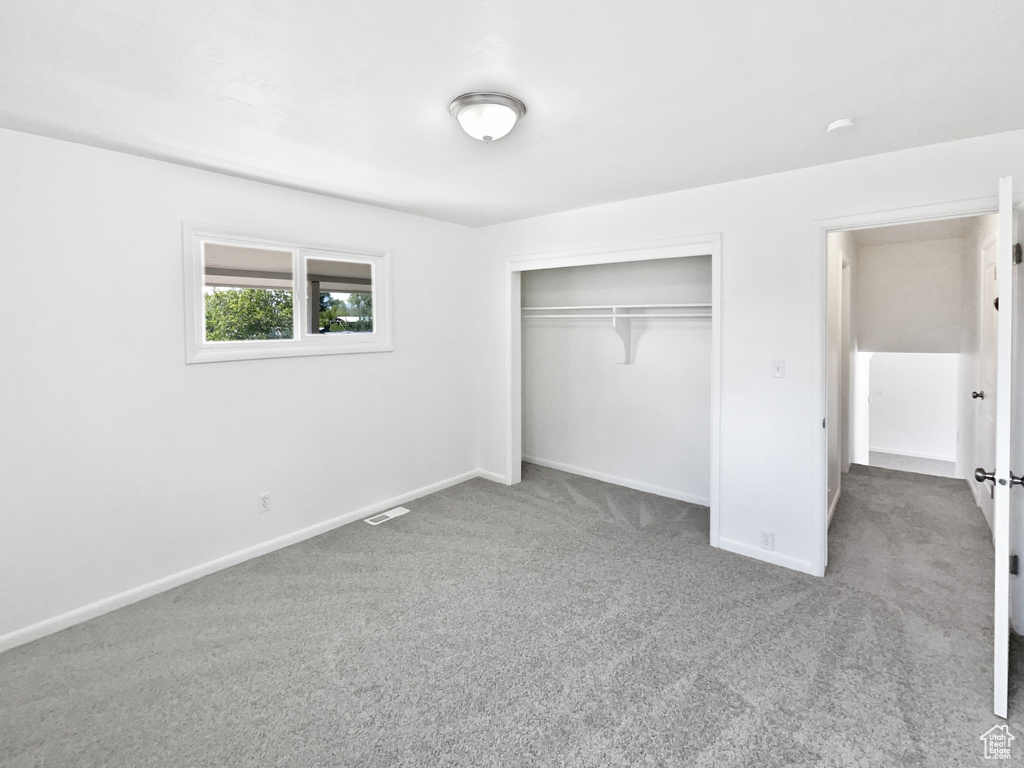 Unfurnished bedroom with carpet floors, baseboards, and a closet