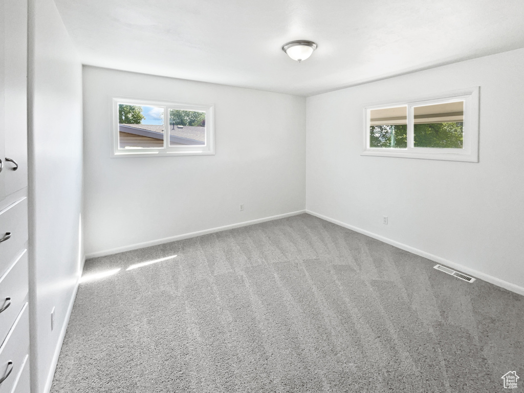 Empty room with healthy amount of natural light, carpet, and baseboards