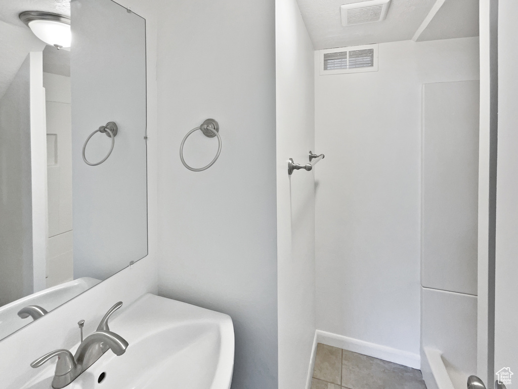 Bathroom featuring a sink, tile patterned floors, and baseboards