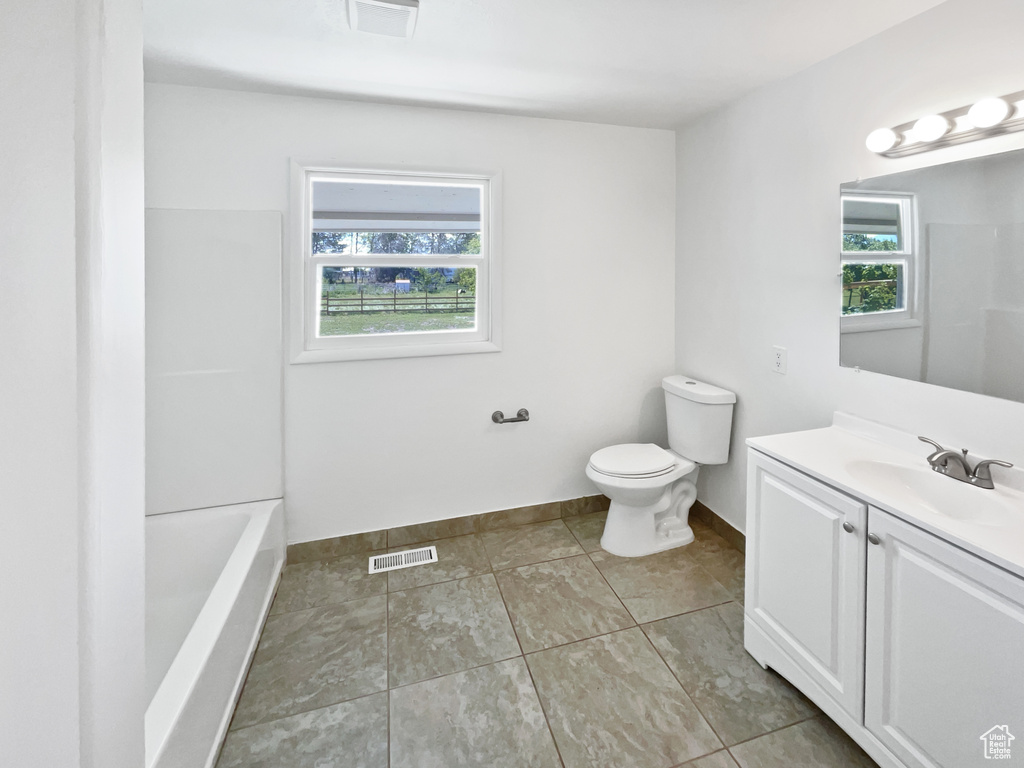 Bathroom featuring toilet, vanity, baseboards, a shower, and a tub to relax in