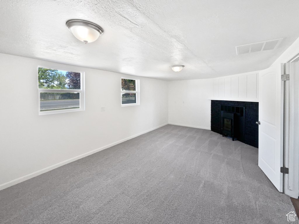Below grade area with carpet floors, a fireplace, plenty of natural light, baseboards, and a textured ceiling