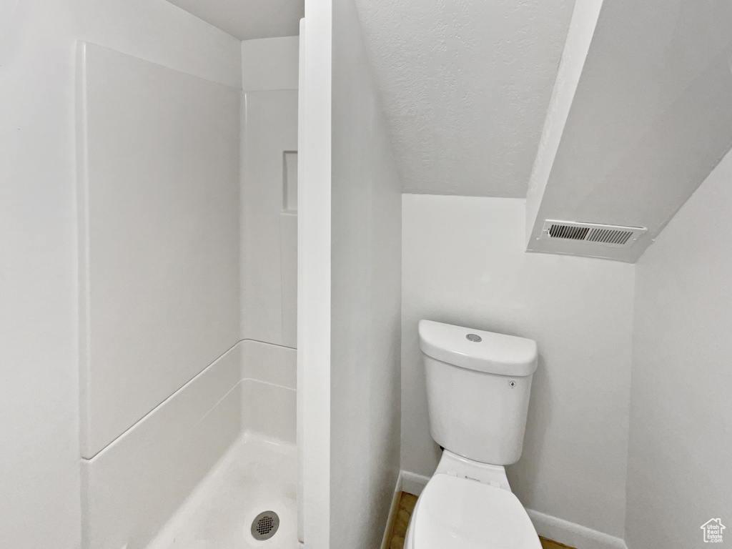 Full bath with toilet, baseboards, and a shower stall