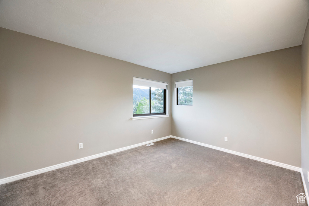 Spare room featuring baseboards and dark colored carpet