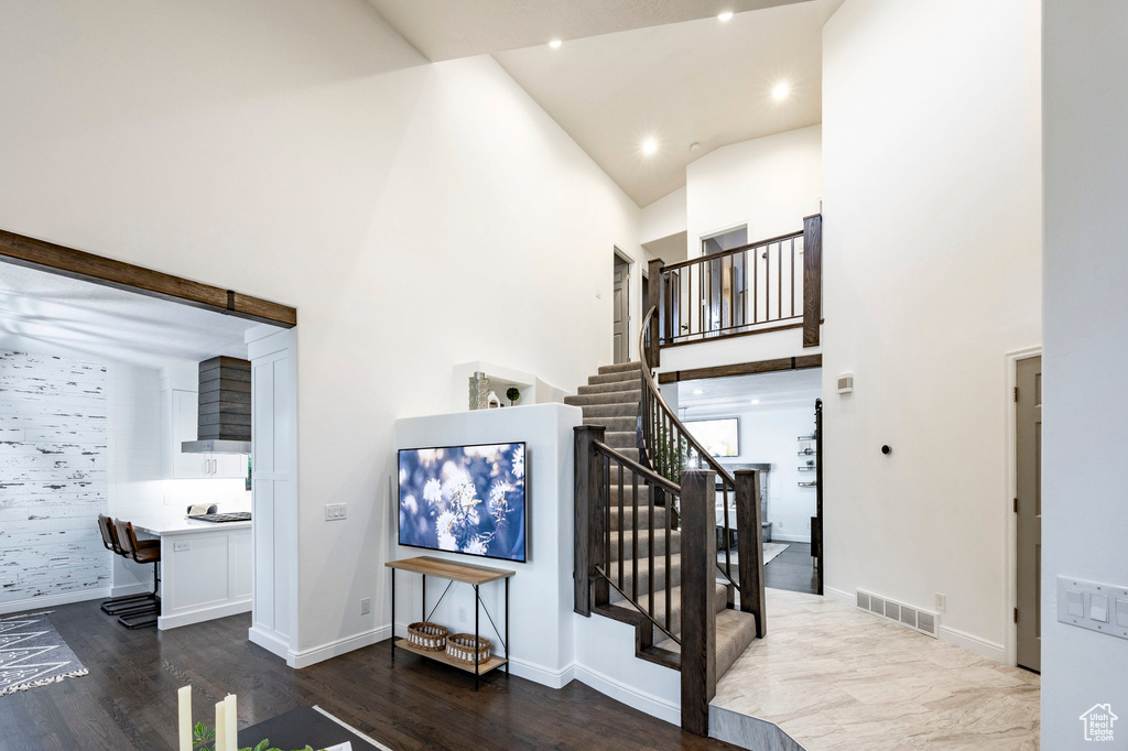 Stairs with high vaulted ceiling, wood finished floors, baseboards, and recessed lighting
