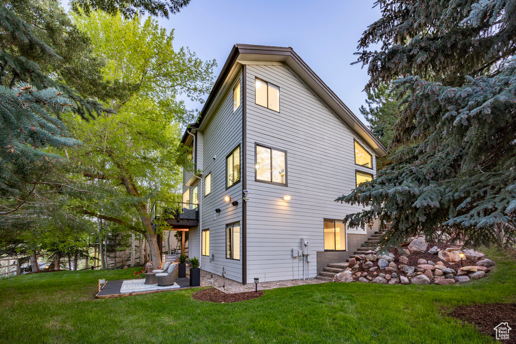Rear view of property featuring stairway, a patio area, a lawn, an outdoor hangout area, and a balcony