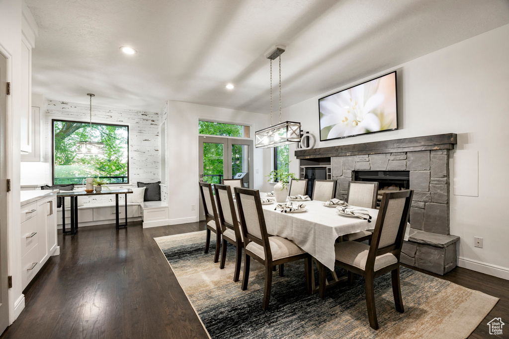 Dining room with a chandelier, a fireplace, baseboards, dark wood-type flooring, and recessed lighting