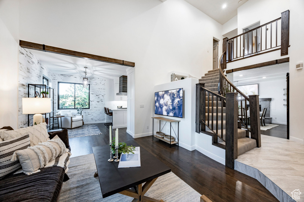Living room featuring wood finished floors, a towering ceiling, stairs, baseboards, and recessed lighting