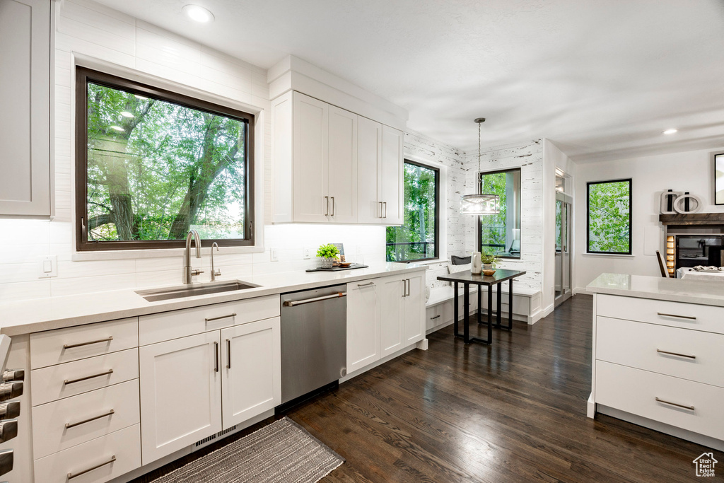 Kitchen with dishwasher, a sink, light countertops, white cabinetry, and recessed lighting