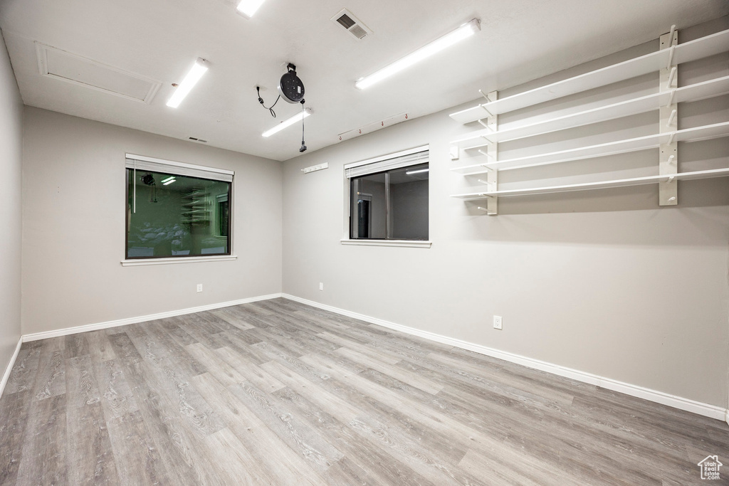 Empty room with wood finished floors, baseboards, and attic access