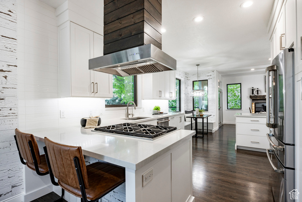 Kitchen with high quality fridge, a sink, a peninsula, baseboards, and white cabinetry