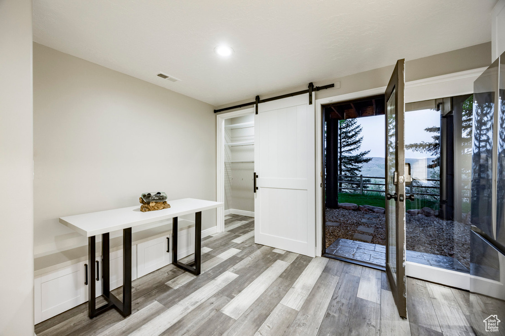 Unfurnished dining area featuring a barn door, wood finished floors, and recessed lighting