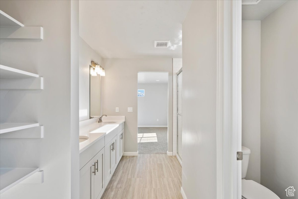 Bathroom with double vanity, toilet, a stall shower, and baseboards