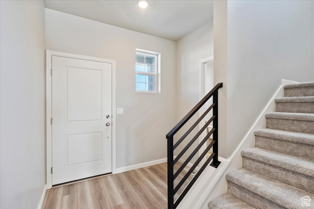 Entrance foyer featuring stairs, light wood-type flooring, and baseboards