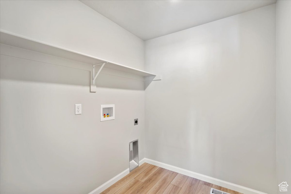 Laundry area with hookup for a washing machine, baseboards, light wood finished floors, and hookup for an electric dryer
