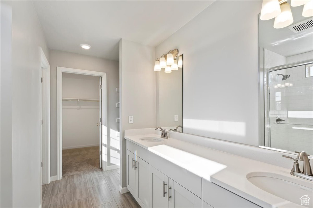 Full bathroom featuring a shower stall, a walk in closet, double vanity, baseboards, and recessed lighting