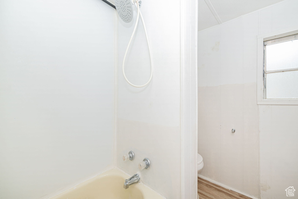 Full bathroom featuring toilet, wood finished floors, and tub / shower combination