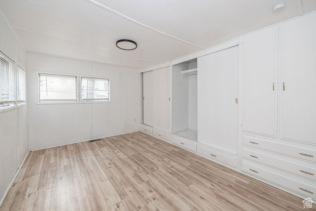 Unfurnished bedroom with light wood-type flooring and two closets