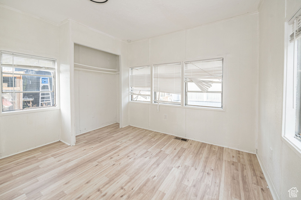 Unfurnished bedroom featuring wood finished floors, a closet, and multiple windows