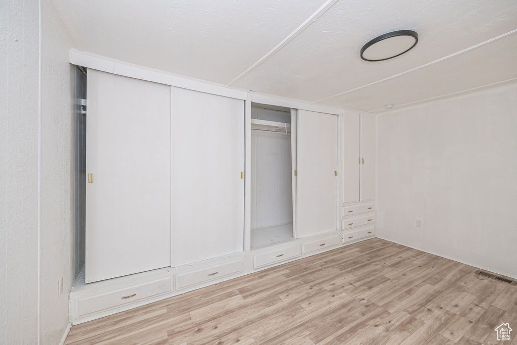 Unfurnished bedroom featuring light wood-style floors and two closets