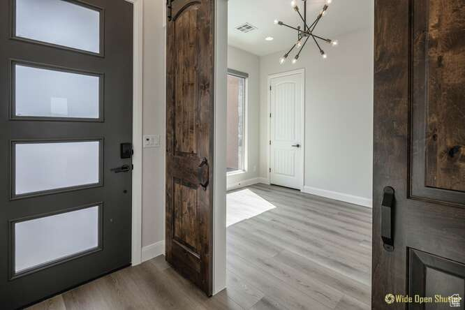 Foyer featuring a chandelier, baseboards, and wood finished floors