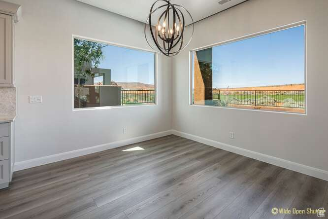 Unfurnished dining area with a chandelier, wood finished floors, and baseboards